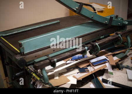 Große Guillotine für das Schneiden von Papier mit der Klinge in einem niedrigen Winkel Nahaufnahme über unsaubere Arbeit Schneidwerk angehoben Stockfoto
