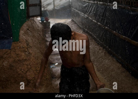 Ein Junge sammelt das Wasser bei starkem Regen in Chakmakul, einem der Camps beherbergt über 800.000 Rohingya-flüchtlinge, Cox's Bazar, Bangladesch, 4. Juli 2018 Stockfoto