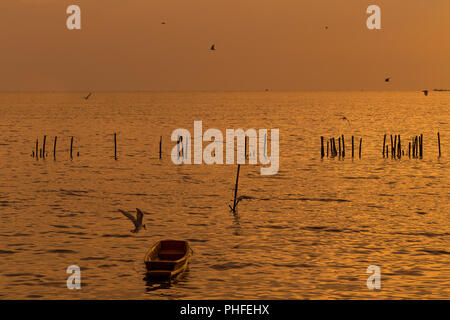 Lonely Holz- fischer Boot mit den Möwen bei Sonnenuntergang/Sonnenaufgang auf dem Meer eine Freiheit und friedlich Stockfoto