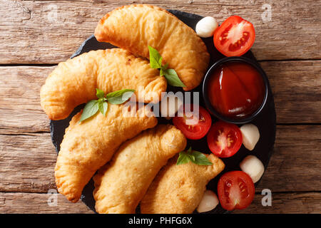 Würzige typische Straße italienisches Essen: Gebratene panzerotti mit Tomatensauce, Kräuter und mozzarella Close-up auf einem schwarzen Brett. Horizontal oben Ansicht von oben Stockfoto