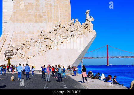 Lissabon, Portugal - März 27, 2018: die Menschen in der Nähe des Flusses Tejo, Ponte de 25 Abril Brücke und das Denkmal der Entdeckungen der Portugiesischen Exp gewidmet Stockfoto