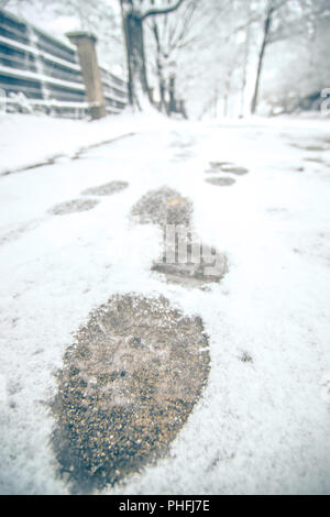 Zeigen Fußspuren im Schnee auf dem Bürgersteig entlang der Park Stockfoto