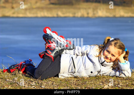 junges Mädchen in Rollschuhe liegt auf dem Boden Stockfoto