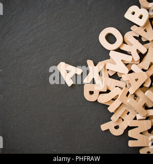 Viele Holz- Buchstaben auf schwarzem Hintergrund. Kopieren Sie Platz. Stockfoto