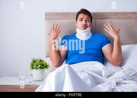 Junger Mann mit Nackenschmerzen im Bett Stockfoto