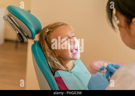 Blonde Mädchen an den Zahnarzt. Ein Zahnarzt untersucht die Zähne eines kleinen Mädchens. Stockfoto