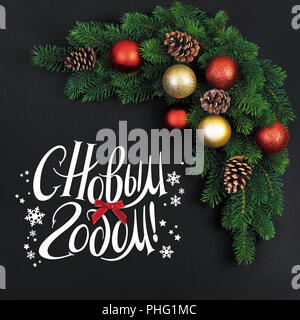 Weihnachten Tannenzweigen mit Dekorationen auf schwarzem Hintergrund und und wünscht ein frohes Neues Jahr! In Russisch Stockfoto