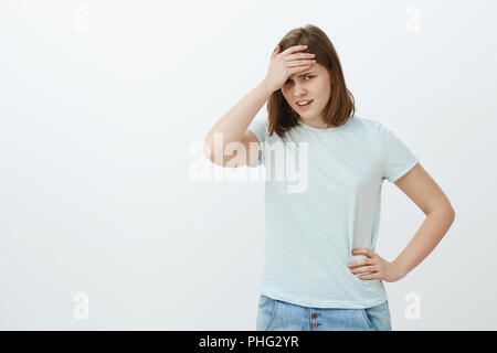 Mädchen Gefühl gedemütigt zu sehen, Mama in der Nähe der Universität. Unbeholfen unzufrieden und peinlich nette junge Frau in t-shirt mit Gesicht mit Palm auf der Stirn von unter Stirn unzufrieden Stockfoto