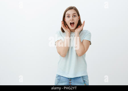 Überrascht und amüsiert Mädchen nicht glauben kann, eigenen Ohren. Portrait der erstaunt überrascht Begeisterte europäische Frau in trendigen t-shirt kreischen vor Freude und Verwunderung holding Palmen in der Nähe von Gesicht anstarren an Kamera Stockfoto