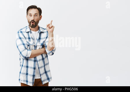 Creative smart Mitarbeiter haben tolle Idee. Portrait von Gut begeistert - auf der Suche reifer Mann mit Bart in kariertes Hemd, der Zeigefinger in Eureka Geste, stehend mit gefalteten Lippen, hinzufügen Vorschlag Stockfoto
