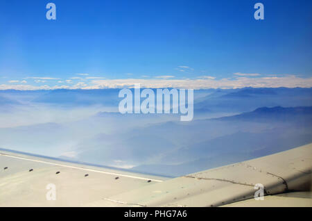 Berge, die unter dem Flugzeug Flügel Stockfoto