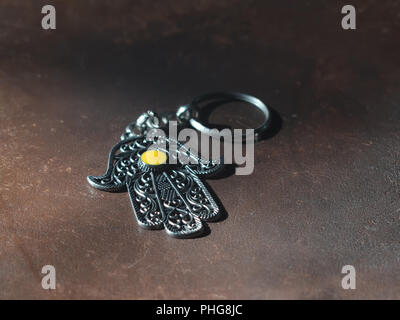 Ein Schlüsselanhänger in der Form von Fatima Hand auf braunem Hintergrund. Altes Symbol und traditionellen moderne touristische Souvenir von Tunesien. Stockfoto