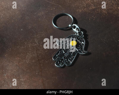 Ein Schlüsselanhänger in der Form von Fatima Hand auf braunem Hintergrund. Altes Symbol und traditionellen moderne touristische Souvenir von Tunesien. Stockfoto