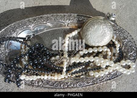 Perlenketten und Taschenuhr auf einem silbernen Tablett Stockfoto