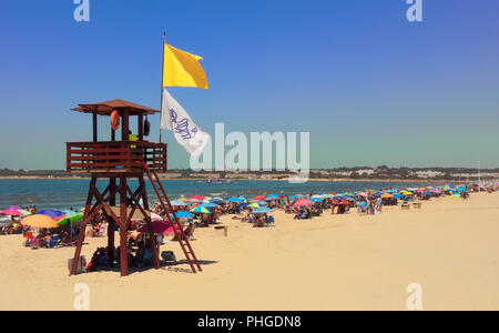 Lifeguard Tower mit gelber Flagge und Quallen Flagge an einem Strand mit vielen Menschen. Stockfoto