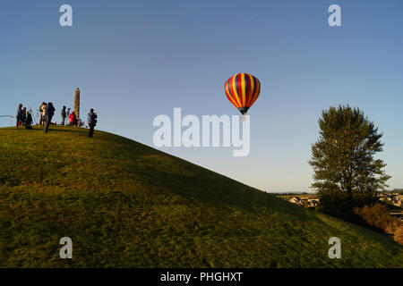 Strathaven Hot Air Balloon Festival 2018 - Kleine Stadt Unterhaltung, bunte Luftballons, Leute auf einem Hügel beobachten die Ballons steigen nach oben, und entfernen Sie sie Stockfoto