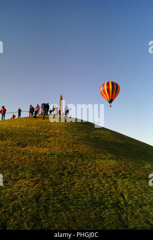 Strathaven Hot Air Balloon Festival 2018 - Kleine Stadt Unterhaltung, bunte Luftballons, Leute auf einem Hügel beobachten die Ballons steigen nach oben, und entfernen Sie sie Stockfoto