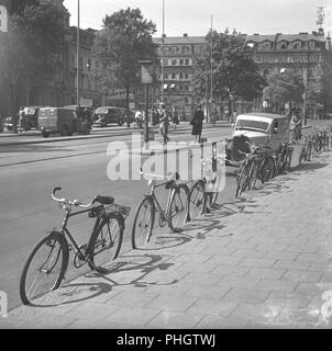 1940 Radfahrer. Fahrräder werden gegen den Bürgersteig in einer belebten Straße in Stockholm City geparkt. Der Ständer für das Fahrrad, ohne es sich zu etwas, sieht so aus, als wenn es noch nicht in ein Element auf der Fahrräder montiert. Die Fahrräder sind alle lehnte sich gegen den Bordstein auf dem Bürgersteig. Mai 1940. Foto Kristoffersson 129-9 Stockfoto