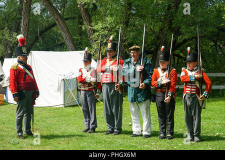 Muskete Demonstration in der Britischen Armee, der Royal Nancy, amerikanischen militärischen Encampment mit Reenactors mit Piraten, Voyageurs und Royal Navy Gun Wuchs Stockfoto