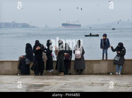 Türkische Frauen in ihren Hajibs und nikabs Blick auf ihre Mobiltelefone durch den Bosporus, Istanbul, Türkei Stockfoto