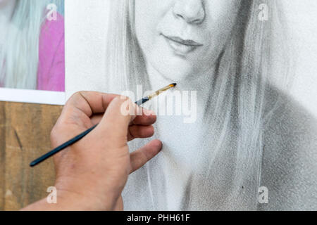 Zeichnet ein Porträt eines Kindes mit einem Pinsel auf Papier von Hand mit einem Pinsel Stockfoto