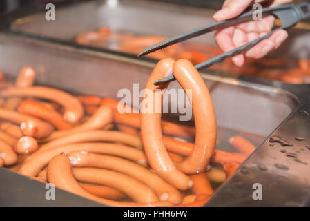Wiener Würstchen fertig gekocht werden mit der Pinzette genommen Stockfoto