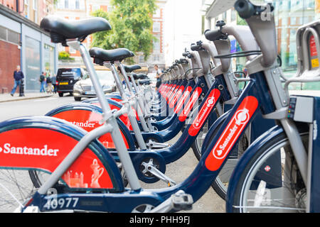 LONDON, ENGLAND, Großbritannien - 31 Juli, 2017: Zeile von Santander rot öffentlichen Verleih Fahrräder bei Docking Station, wie Boris Bikes bekannt Stockfoto