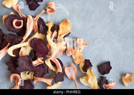 Verschiedenen pflanzlichen Chips auf grauem Hintergrund, kopieren. Verschiedene getrocknete rote Beete, Karotten, Kürbis Gemüse Chips - gesunden veganen Snack. Stockfoto