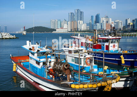 Haeundae Beach, Busan, gesehen von der kleine Fischerhafen mit Booten im Vordergrund und die Diamond Brücke und Stadt in den Hintergrund. Stockfoto
