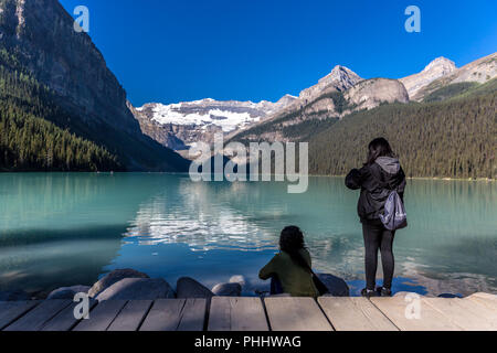 Banff, Kanada - Vor 14 2017 - Gruppe der Touristen vor Lake Moraine in den frühen Morgen. Blauer Himmel, Berge im Hintergrund, Schattierungen von Baum Stockfoto