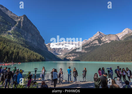 Banff, Kanada - Vor 14 2017 - Gruppe der Touristen vor Lake Moraine in den frühen Morgen. Blauer Himmel, Berge im Hintergrund, Schattierungen von Baum Stockfoto