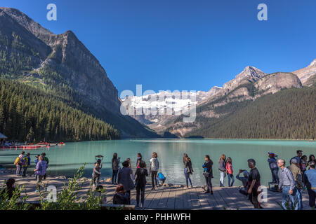 Banff, Kanada - Vor 14 2017 - Gruppe der Touristen vor Lake Moraine in den frühen Morgen. Blauer Himmel, Berge im Hintergrund, Schattierungen von Baum Stockfoto