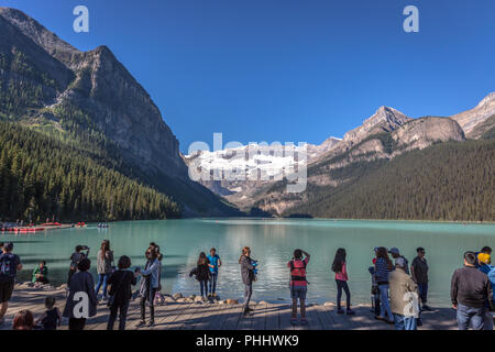 Banff, Kanada - Vor 14 2017 - Gruppe der Touristen vor Lake Moraine in den frühen Morgen. Blauer Himmel, Berge im Hintergrund, Schattierungen von Baum Stockfoto