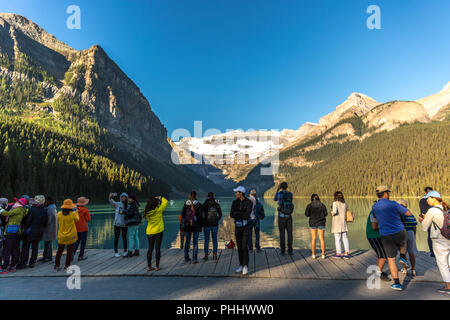 Banff, Kanada - Vor 14 2017 - Gruppe der Touristen vor Lake Moraine in den frühen Morgen. Blauer Himmel, Berge im Hintergrund, Schattierungen von Baum Stockfoto