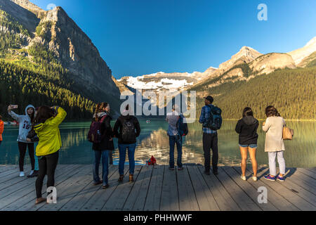 Banff, Kanada - Vor 14 2017 - Gruppe der Touristen vor Lake Moraine in den frühen Morgen. Blauer Himmel, Berge im Hintergrund, Schattierungen von Baum Stockfoto