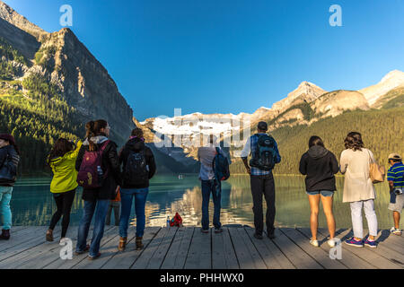 Banff, Kanada - Vor 14 2017 - Gruppe der Touristen vor Lake Moraine in den frühen Morgen. Blauer Himmel, Berge im Hintergrund, Schattierungen von Baum Stockfoto