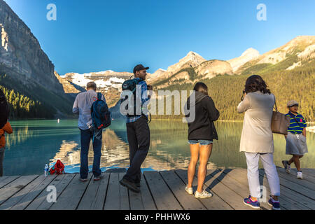 Banff, Kanada - Vor 14 2017 - Gruppe der Touristen vor Lake Moraine in den frühen Morgen. Blauer Himmel, Berge im Hintergrund, Schattierungen von Baum Stockfoto