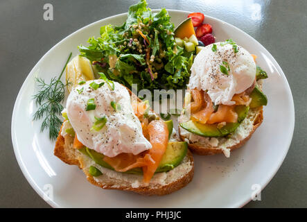 Eggs Royale, zwei pochierte Eier mit Räucherlachs und Avocado auf Toast mit gemischtem Salat in einem Bistro in Montreal Stockfoto