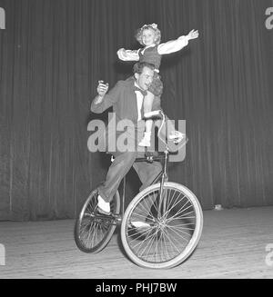 1950 s Fahrrad Performer. Ein Mann ist ausgleichend ein Mädchen auf seine Schulter, während rund um Radfahren auf einer Theaterbühne. Die Akte wird als Bronnleys Fahrrad Gleichgewicht handeln. Schweden 1951 Stockfoto