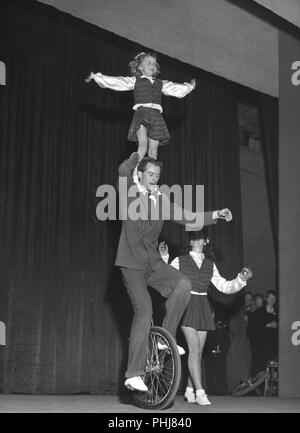 1950 s Fahrrad Performer. Ein Mann ist ausgleichend ein Mädchen auf seine Schulter, während rund um Radfahren auf einer Theaterbühne. Die Akte wird als Bronnleys Fahrrad Gleichgewicht handeln. Schweden 1951. Foto Kristoffersson werden 61-5 Stockfoto