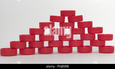 Flache Pyramide voller Löcher zwischen zusammengesetzten Elemente. Aus rotem gerippten Kunststoff Flasche Kappen. closeup Stockfoto