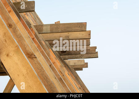 Einfamilienhaus Bau. Bau eines neuen Holz gerahmt Haus. Holz Dachsparren gegen den blauen Himmel bei Sonnenuntergang. Stockfoto