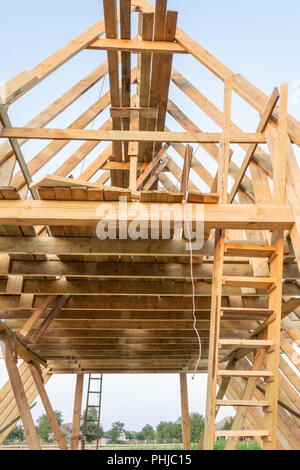 Einfamilienhaus Bau. Bau eines neuen Holz gerahmt Haus. Holz Dachsparren gegen den blauen Himmel bei Sonnenuntergang. Stockfoto