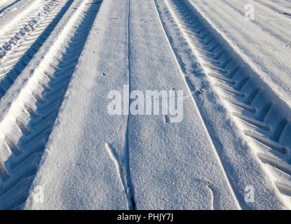 Tiefe Spuren von den Reifen eines großen, möglicherweise Cargo, Auto oder Traktor auf weißen Schnee im Winter, Off Road Stockfoto