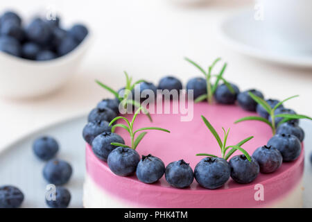 Die zweifarbige Blueberry mini Käsekuchen. Runde keine Backen Käsekuchen, Schüssel mit Blaubeeren, Tasse Kaffee und Schüssel mit Zucker. Top Kuchen dekoriert von Stockfoto