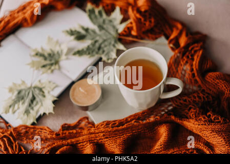 Herbst Herbst Konzept, Notebook, roter Schal, Herbst Blatt, Kerze und heiße Tasse Tee, hygge Stockfoto