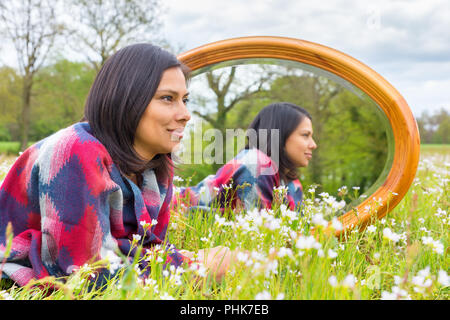 Frau in blühende Wiese mit Spiegel Lügen Stockfoto