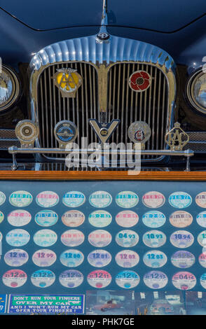 Den Frontgrill eines klassischen oder colectors Auto mit einer Reihe von altmodischen Steuer Discs oder road fund Lizenzen in einem Rahmen. Stockfoto