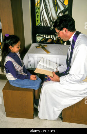Der katholische Priester Lesen der Bibel auf das Kind während der Versöhnung. © Myrleen Pearson.... Ferguson Cate Stockfoto
