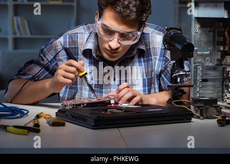 Junge Reparaturtechniker löten elektrische Teile auf motherboar Stockfoto